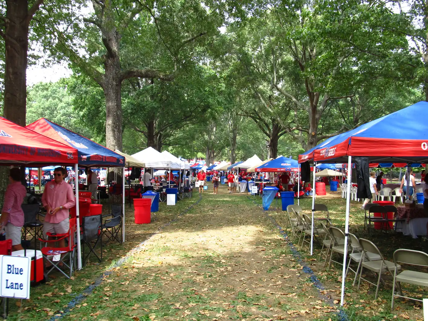 Shade trees and tents along a lane in the Grove at the University of Mississippi in Oxford.