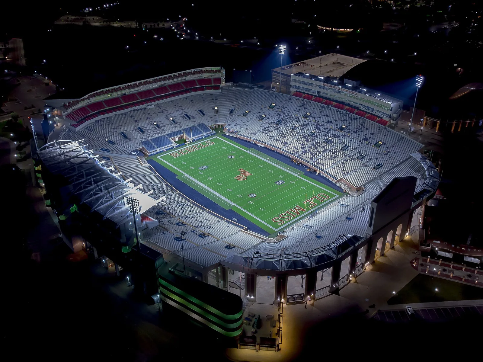 Vaught-Hemingway Stadium lit up at night on the University of Mississippi campus in Oxford, seen from the air.