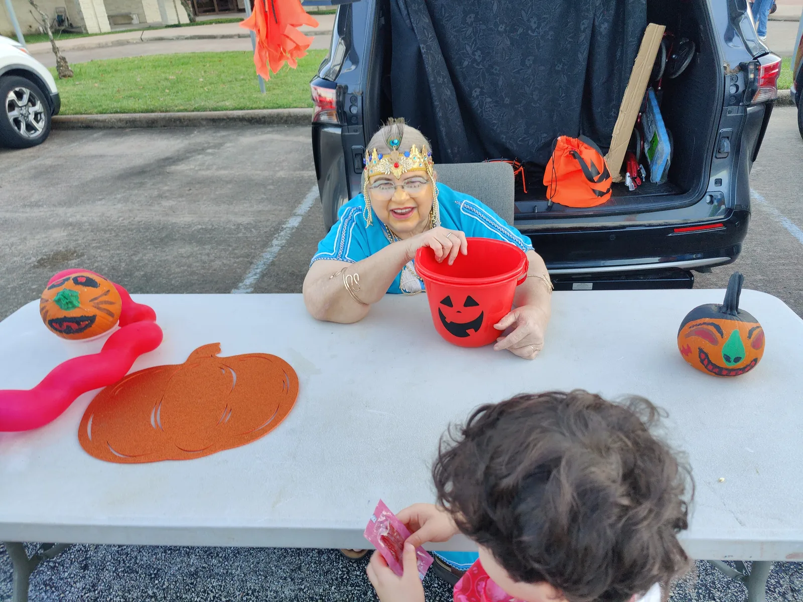 A volunteer in costume hands out candy from a decorated car trunk at a church trunk-or-treat.