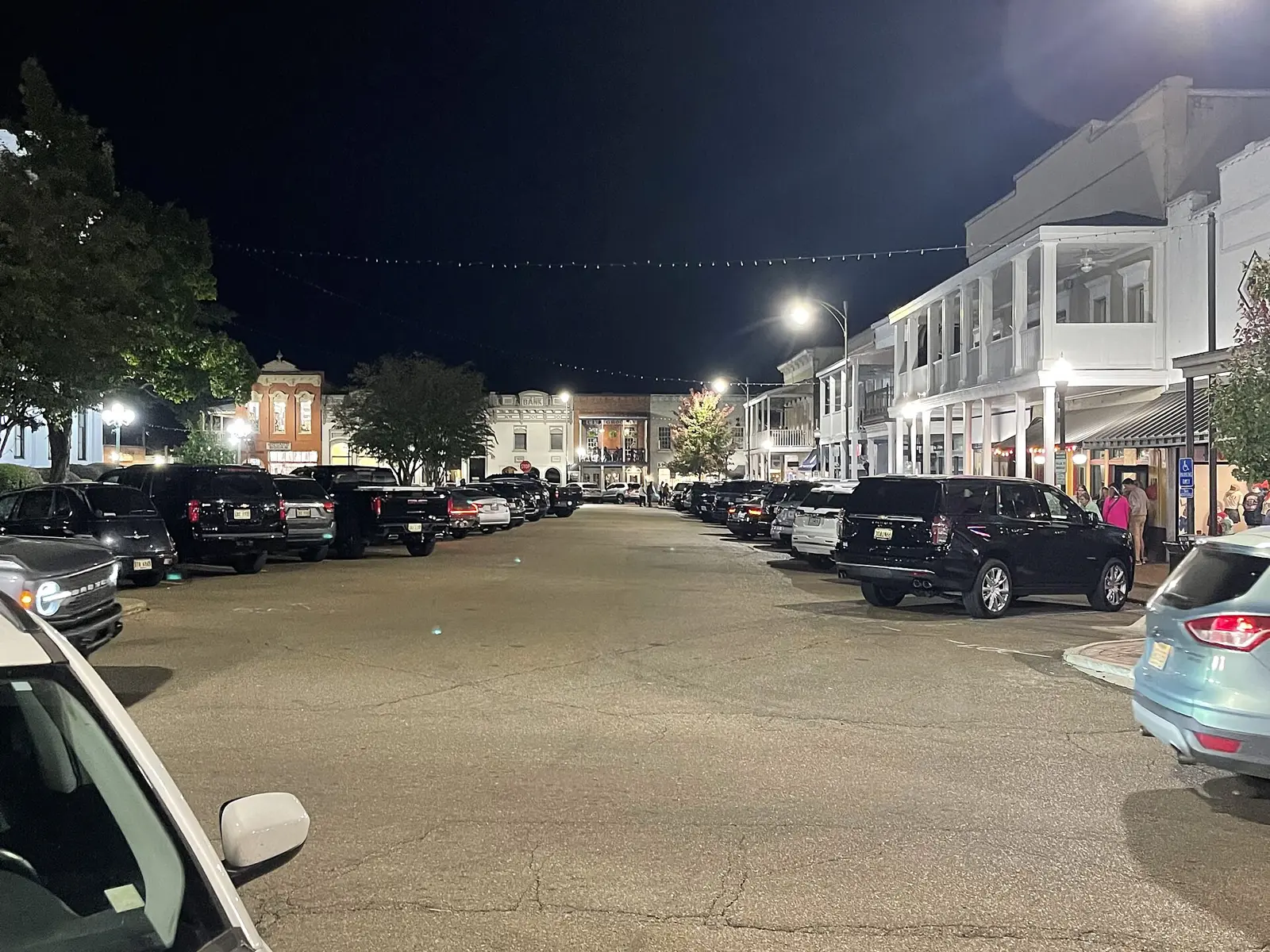 Restaurants and balconies lit up along a side of the Square in downtown Oxford at night.