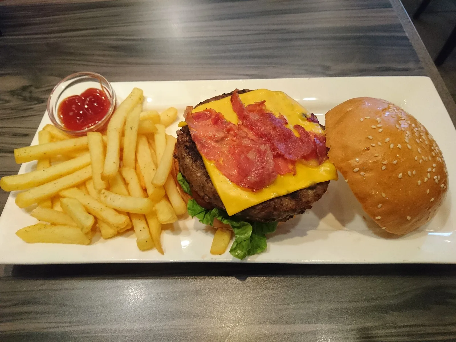 A bacon cheeseburger with french fries on a plate.